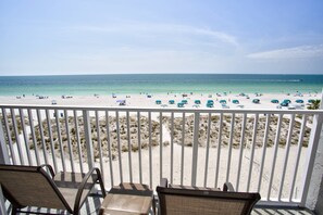 A beach view from a balcony with white railings, beach chairs, and umbrellas. - Amazing Beachfront Studio w/Private Balcony! Beachside Pool, Tiki Bar, Sand Volleyball, Fishing Dock (Treasure Island)