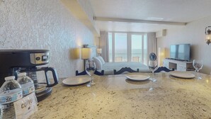 Ein Hotelzimmer mit Bett, Fernseher, einer Kaffeemaschine und Meerblick.