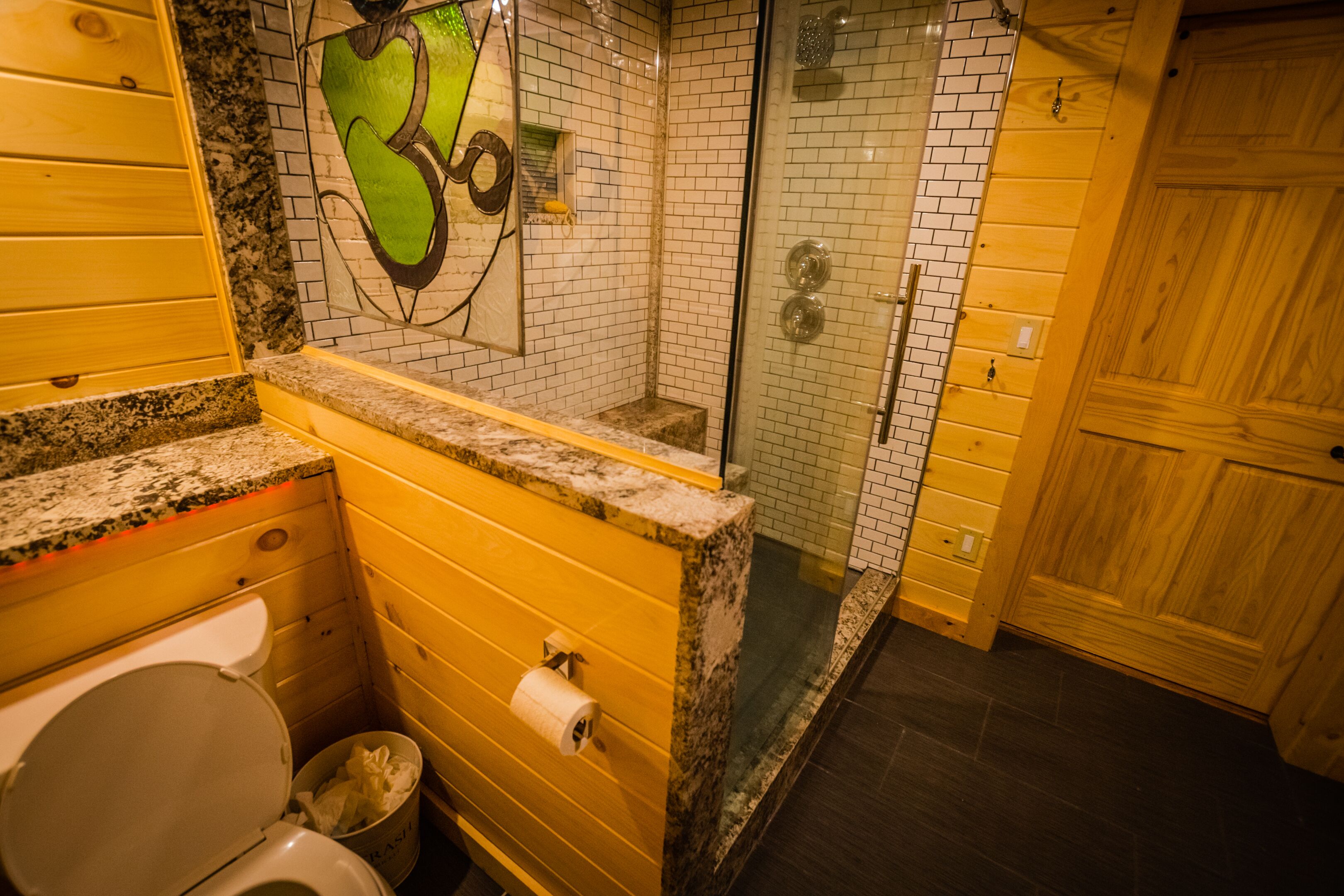 Ein Badezimmer mit Toilette, Dusche und einem Holzkosmetikschrank.