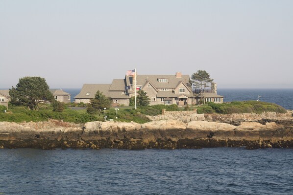 A coastal house with a flag, situated on rocky terrain with a view of the sea. - Classic, summer cottage with all the amenities! (Kennebunkport)