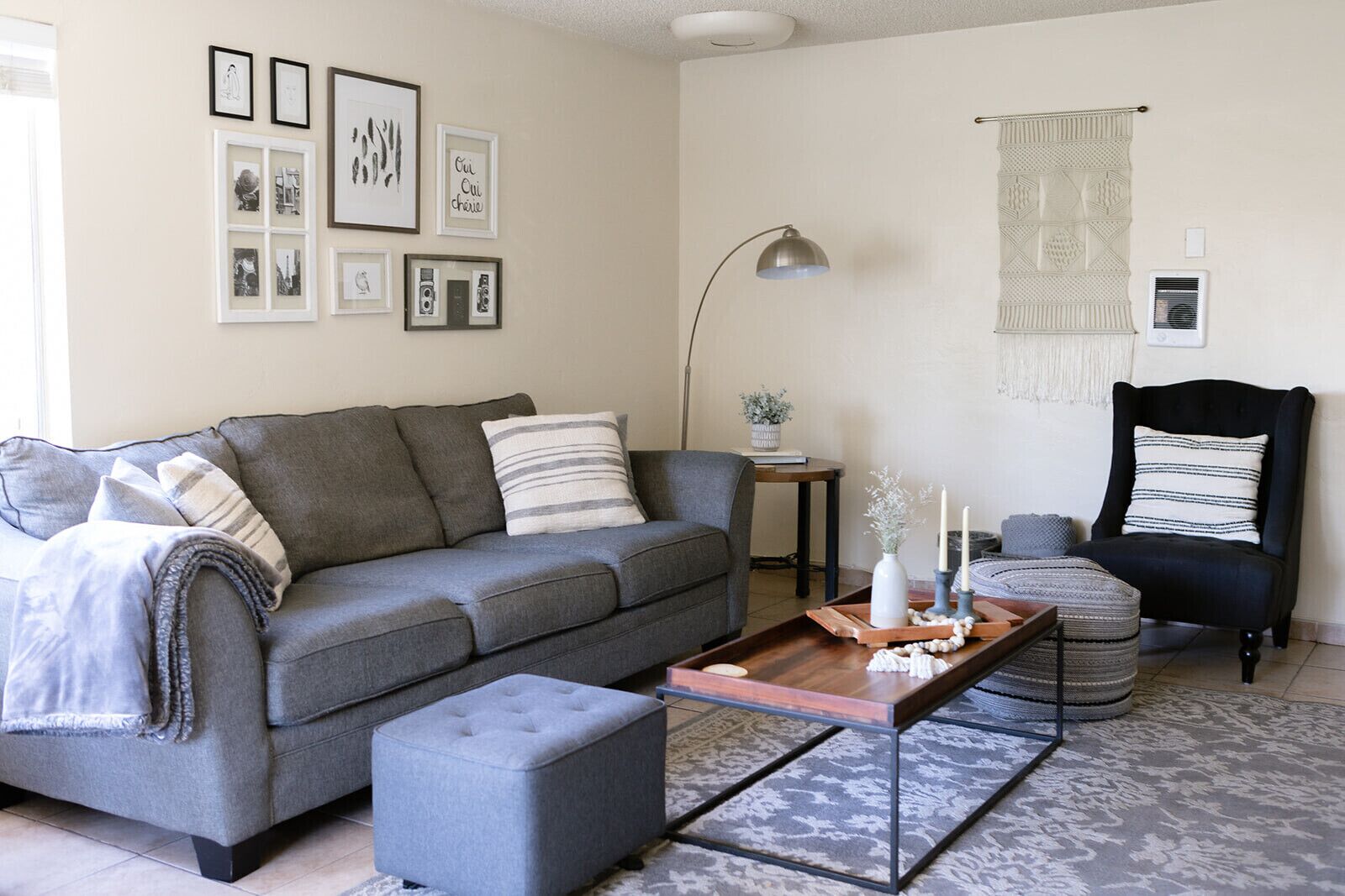 A living room with a grey sofa, a black armchair, a coffee table, and a side table with a plant.