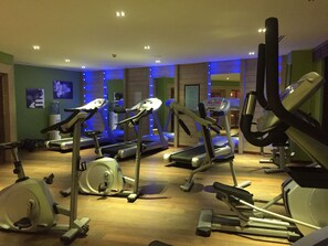 Un gimnasio con cintas de correr, elípticas y un dispensador de agua.