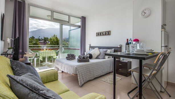 A modern bedroom with a bed, a desk, and a balcony with a view of mountains. - Incredible Relax Studio with Mountain Views and High Speed WIFI (Puerto de la Cruz)