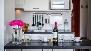 A kitchen with white cabinets, a microwave, and a sink. There is a table with a wine bottle, a vase with flowers, and white dishes. - Incredible Relax Studio with Mountain Views and High Speed WIFI (Puerto de la Cruz)
