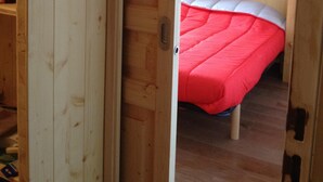 Una habitación de madera con una cama, un armario y una puerta.