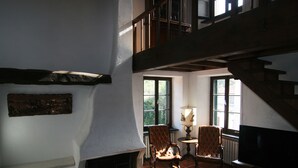 A room with a fireplace, a chair, a television, and a window with a view of greenery. - Centrally located, yet secluded house on the outskirts of Dolcedo (Dolcedo)