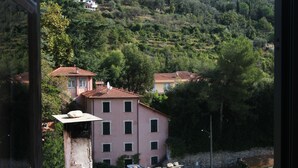 A view of a hillside with buildings, including a pink building with a tiled roof and a white building with a balcony. - Centrally located, yet secluded house on the outskirts of Dolcedo (Dolcedo)