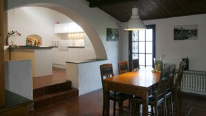 A dining area with a wooden table and chairs, a kitchen in the background, and a window with decorative ironwork. - Centrally located, yet secluded house on the outskirts of Dolcedo (Dolcedo)