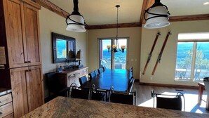Une cuisine dotée d’un plan de travail en granit, de meubles en bois, d’un coin repas avec une grande table et des chaises, et offrant une vue par une fenêtre.