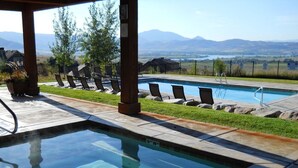 Une piscine à l’eau claire, des chaises longues et une vue sur les montagnes en arrière-plan.