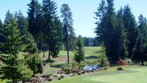 Un parcours de golf avec un étang, des arbres et un ciel dégagé.