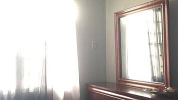 Un dormitorio con cama, cómoda, espejo y equipo de aire acondicionado.