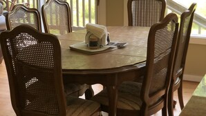 Un coin repas avec une table ronde et six chaises en osier.
