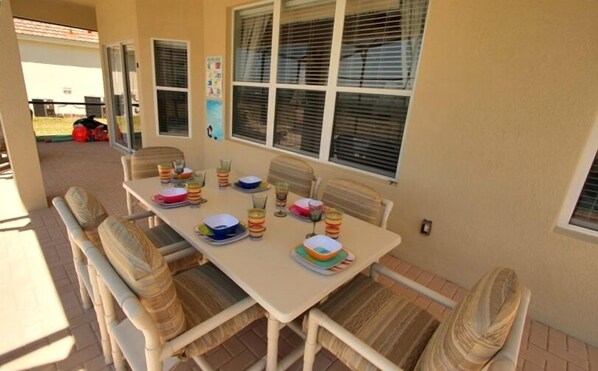 An outdoor dining area with a table set for four, surrounded by cushioned chairs.