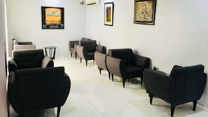 Un área de espera con varios sofás y sillones, una pequeña mesa y dos obras de arte enmarcadas en las paredes.