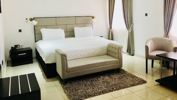 Un dormitorio con cama, mesita de noche, silla y una pequeña mesa.