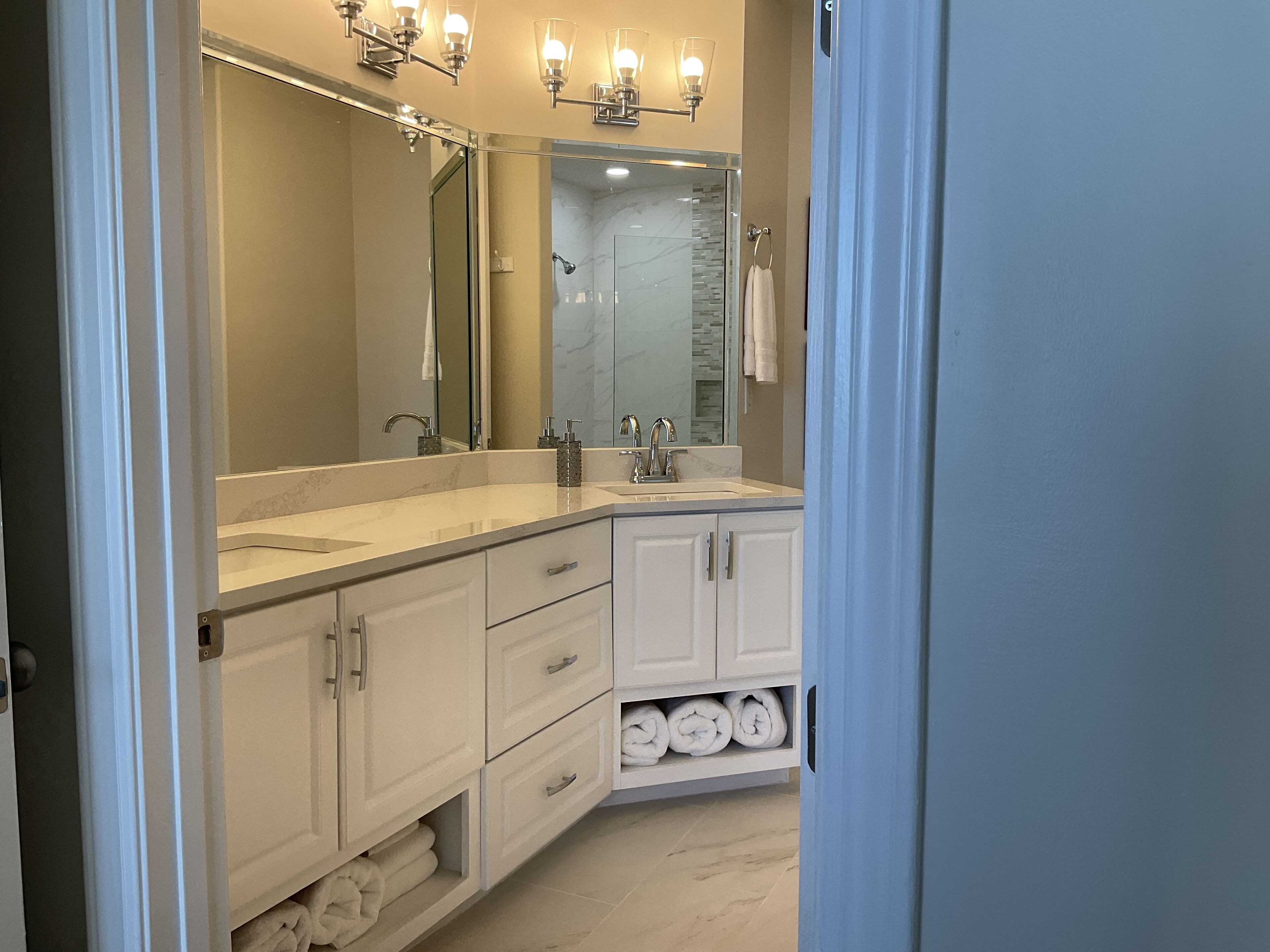 A modern bathroom with a large mirror, two sinks, and a towel rack.