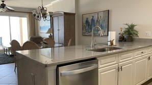 A modern kitchen with a built-in dishwasher, stainless steel appliances, and white cabinetry.
