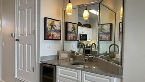 A modern bathroom with a large mirror, a sink, and a built-in oven.