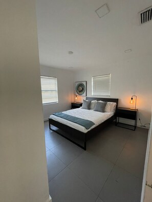 Een moderne slaapkamer met een bed, twee nachtkastjes en een wandlamp.