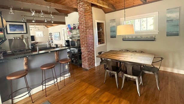 A spacious kitchen with a large island, bar stools, and a dining table with chairs. - Stunningly Remodeled Historic Home Near Downtown (Bozeman)
