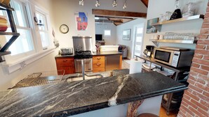 A modern kitchen with granite countertops, stainless steel appliances, and a brick accent wall. - Stunningly Remodeled Historic Home Near Downtown (Bozeman)