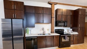 Una cocina moderna con armarios de madera oscura, electrodomésticos de acero inoxidable y techo con vigas de madera.