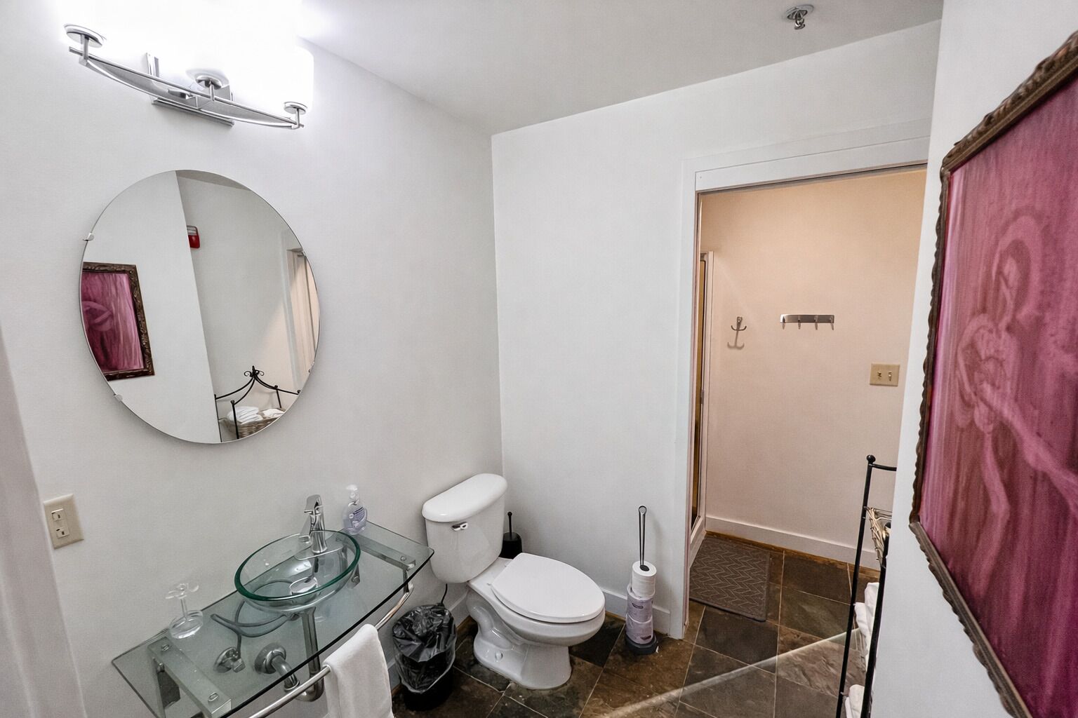 A bathroom with a glass sink, white toilet, and a mirror.