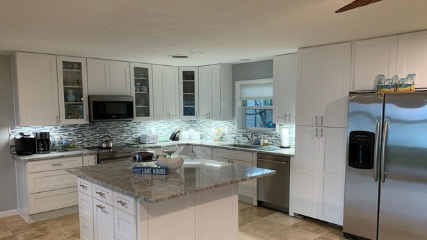 A modern kitchen with white cabinetry, a granite countertop, and stainless steel appliances.
