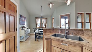 A kitchen with wooden cabinets, a double sink, and a dining area with a table and chairs.