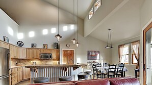 A spacious kitchen with wooden cabinets, a central island, and pendant lighting.