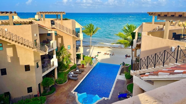 A resort with a swimming pool, beach, and ocean view.