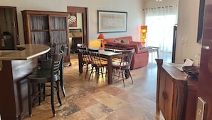 A spacious living area with a dining table and chairs, a sofa, and a ceiling fan.