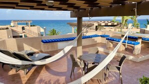 A rooftop terrace with hammocks, seating areas, and a view of the ocean.