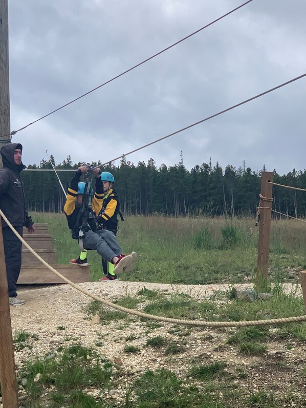 Een persoon met harnas en helm die zich voorbereidt voor een zipline-activiteit.