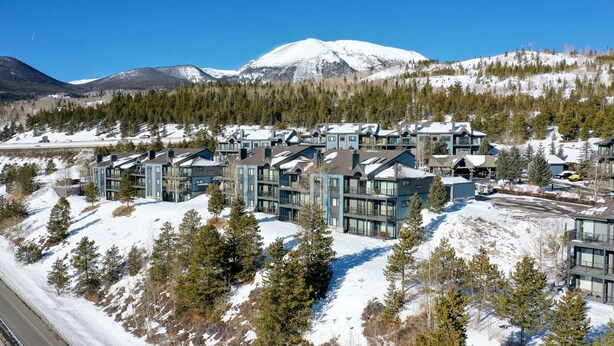 A modern ski resort with multi-story buildings, snow-covered surroundings, and a mountain backdrop.