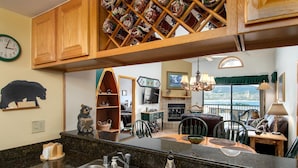 A kitchen with a granite countertop, stainless steel sink, wooden cabinets, and a decorative bear statue.