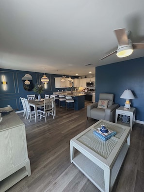 Un salon moderne comprenant un coin repas, une cuisine et un ventilateur de plafond.