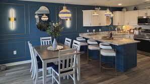 A modern kitchen with a central island, white cabinetry, and pendant lighting.