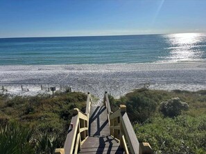 A wooden boardwalk leading to a beach with a clear view of the ocean.
