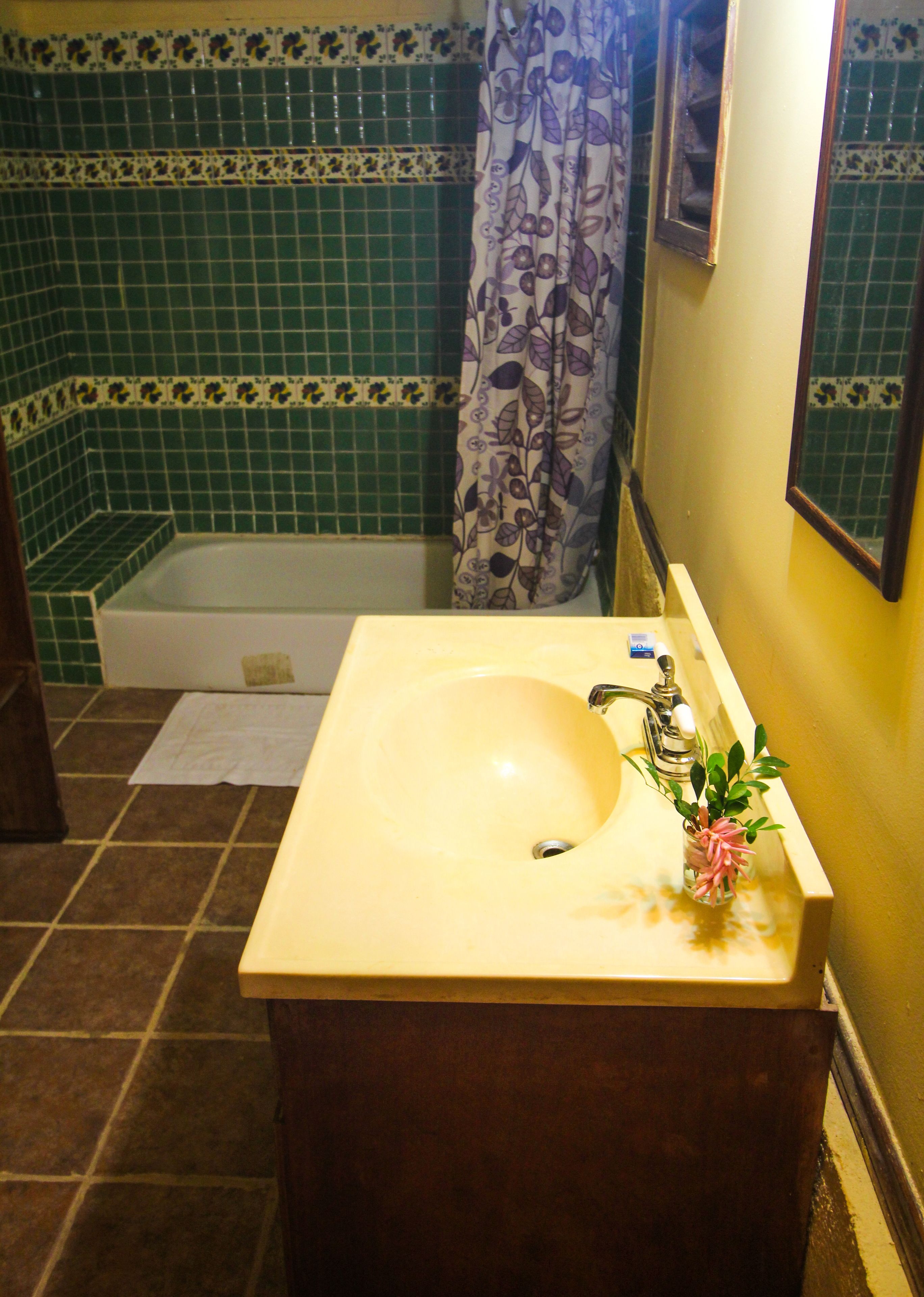 A bathroom with a sink, mirror, and bathtub.
