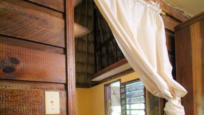 A wooden interior with a red chair, a patterned rug, and a white curtain. - Cohune Palms River Cabanas (San Ignacio)