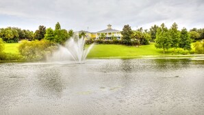 Une fontaine dans un parc, avec un bâtiment en arrière-plan.
