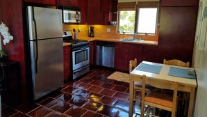 Une cuisine de taille réduite, dotée de meubles en bois fonc é, d’appareils électroménagers en acier inoxydable et d’un sol carrelé.