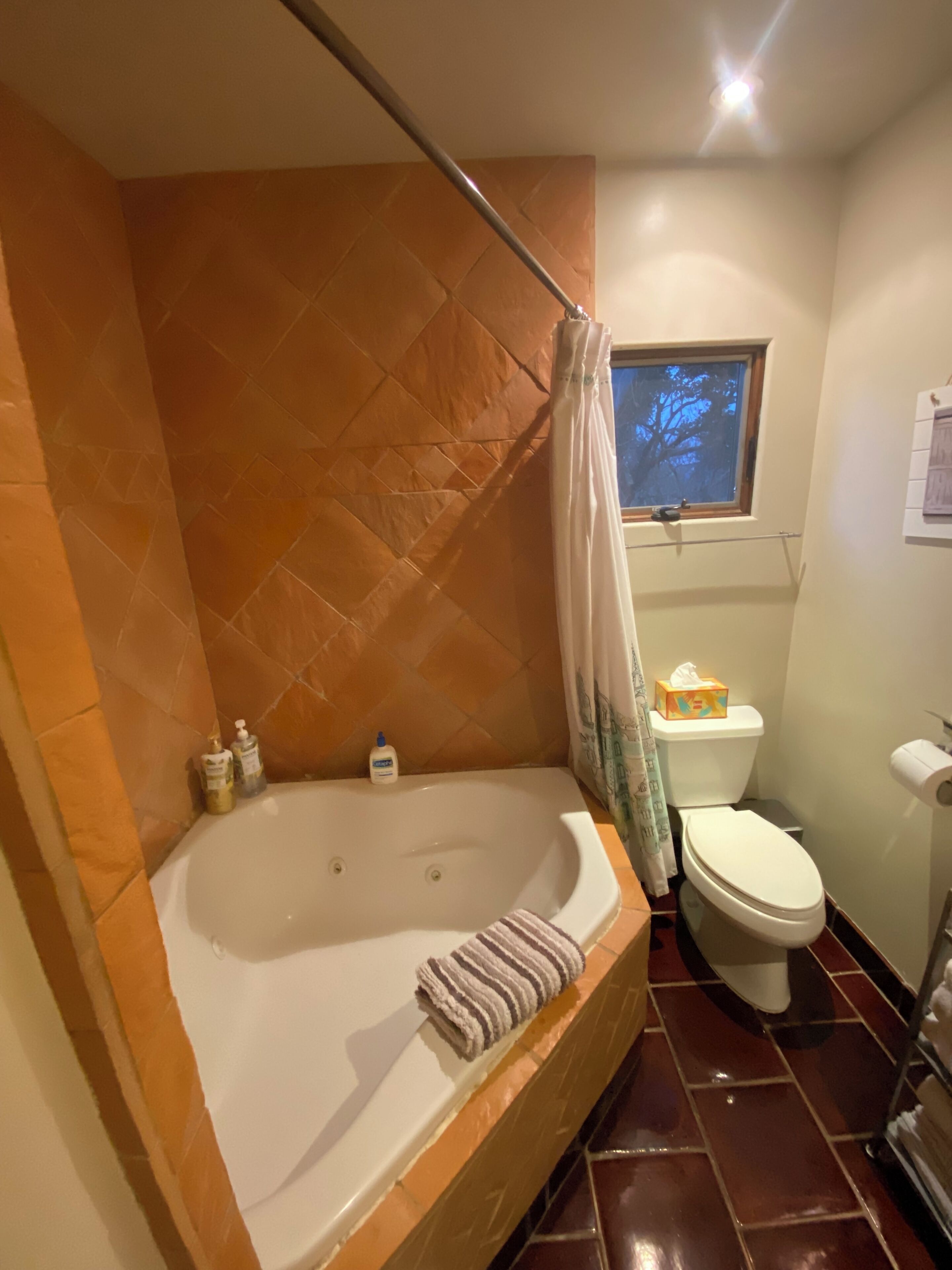 A bathroom with a bathtub, toilet, and a window.