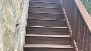 Un escalier en bois avec une rampe métallique, menant le long d’un mur en béton.
