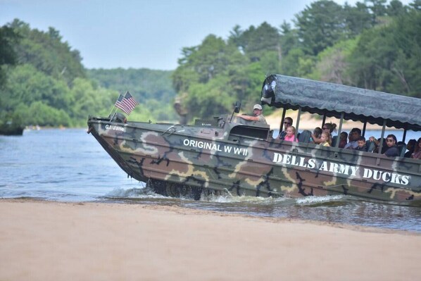 Un bote llamado "Original WW II Dells Army Ducks" con pasajeros y una bandera estadounidense.