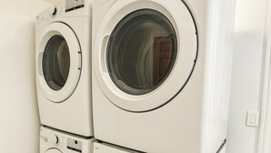 A stack of white front-loading washing machines in a room with light-colored wooden flooring and white walls. - All Decked Out | Arcade Games | Amazing 5 BR |  Huge Deck | Fire Pit | Close to Everything WI Dells (Wisconsin Dells)