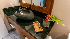 A bathroom with a black granite sink, wooden vanity, and a mirror with a wooden frame.
