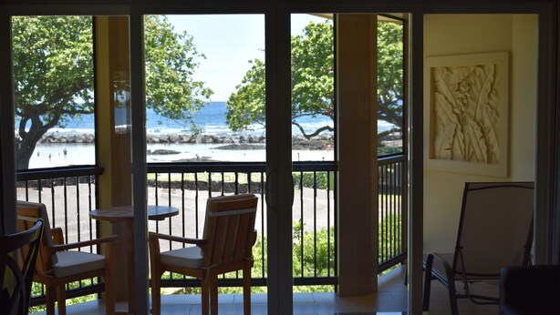 A room with a view of the beach, a table, and two chairs.